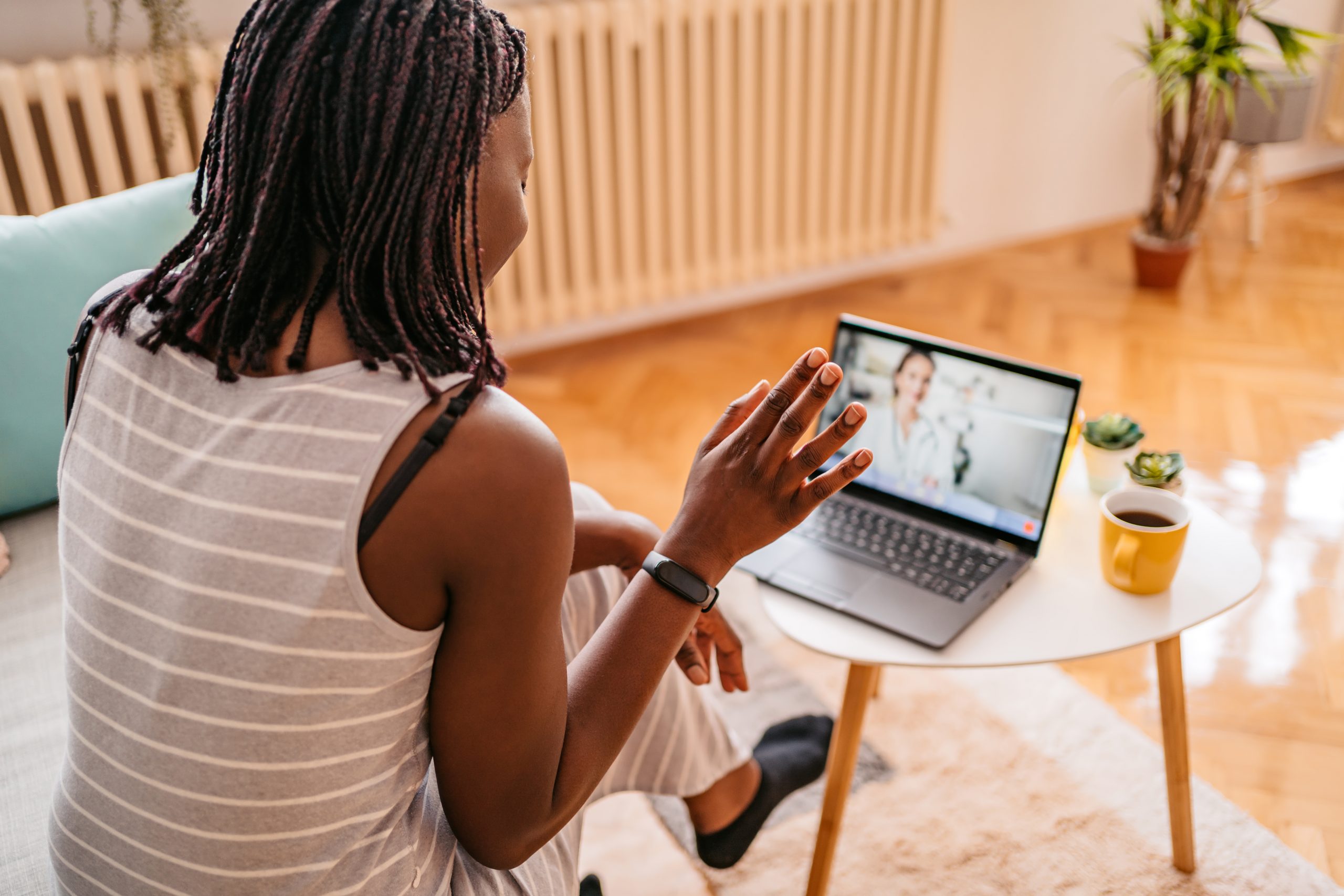 African-American woman Video Conferencing With Doctor On smartphone while sitting on sofa in her home.