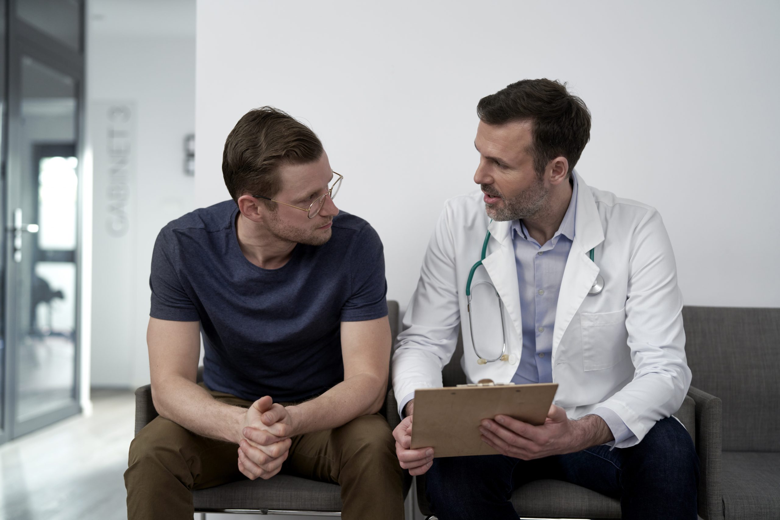 Mature doctor discussing with man at clinic