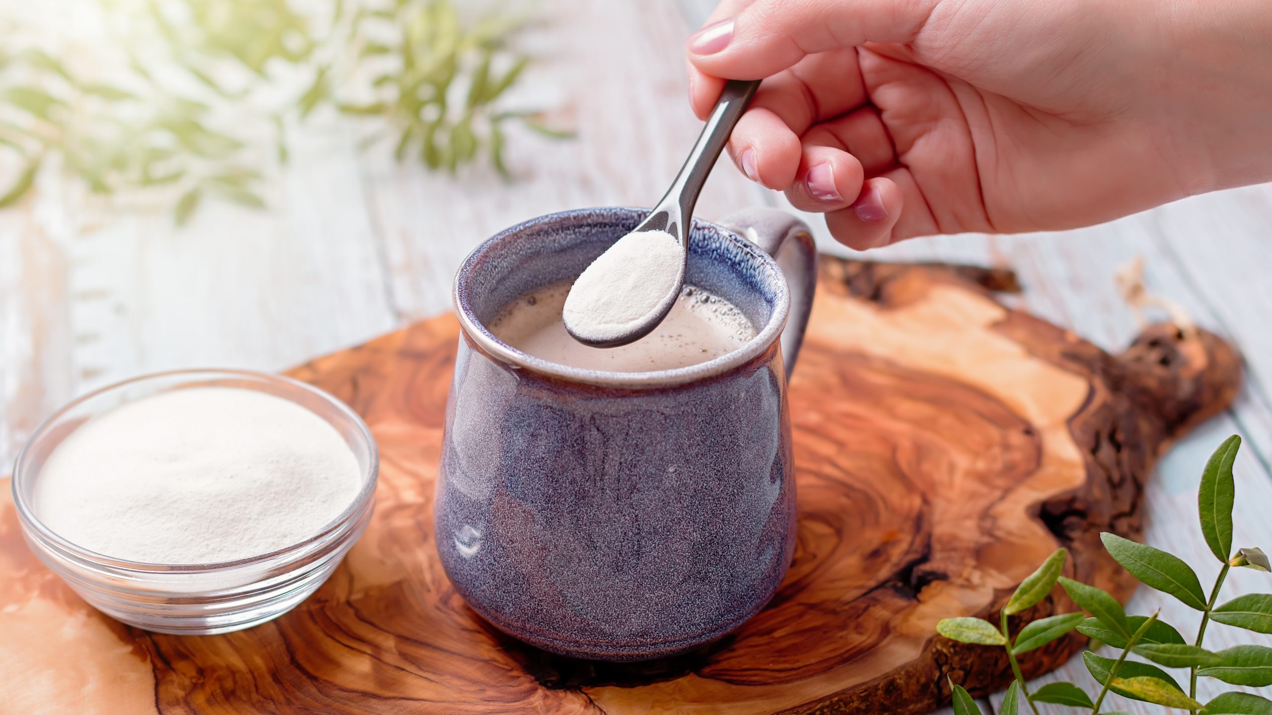 Woman adding collagen powder to her morning coffee.