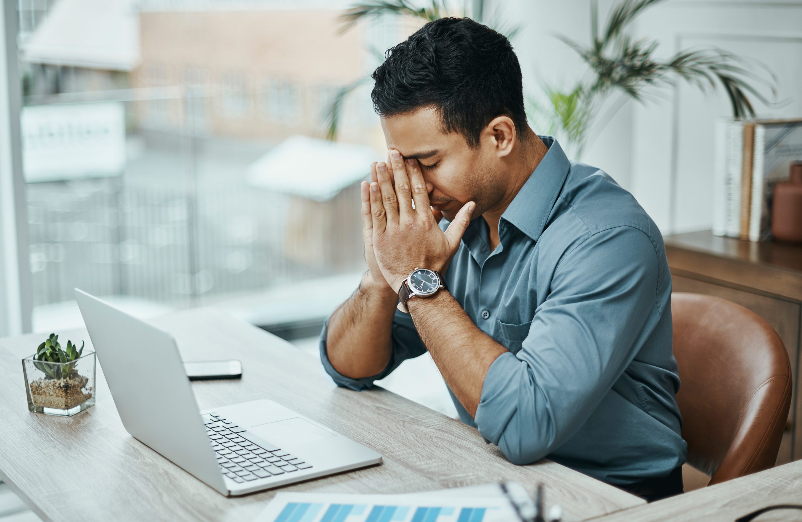 Shot of a young businessman looking stressed while working in a modern office Shot of a young businessman looking stressed while working in a modern office