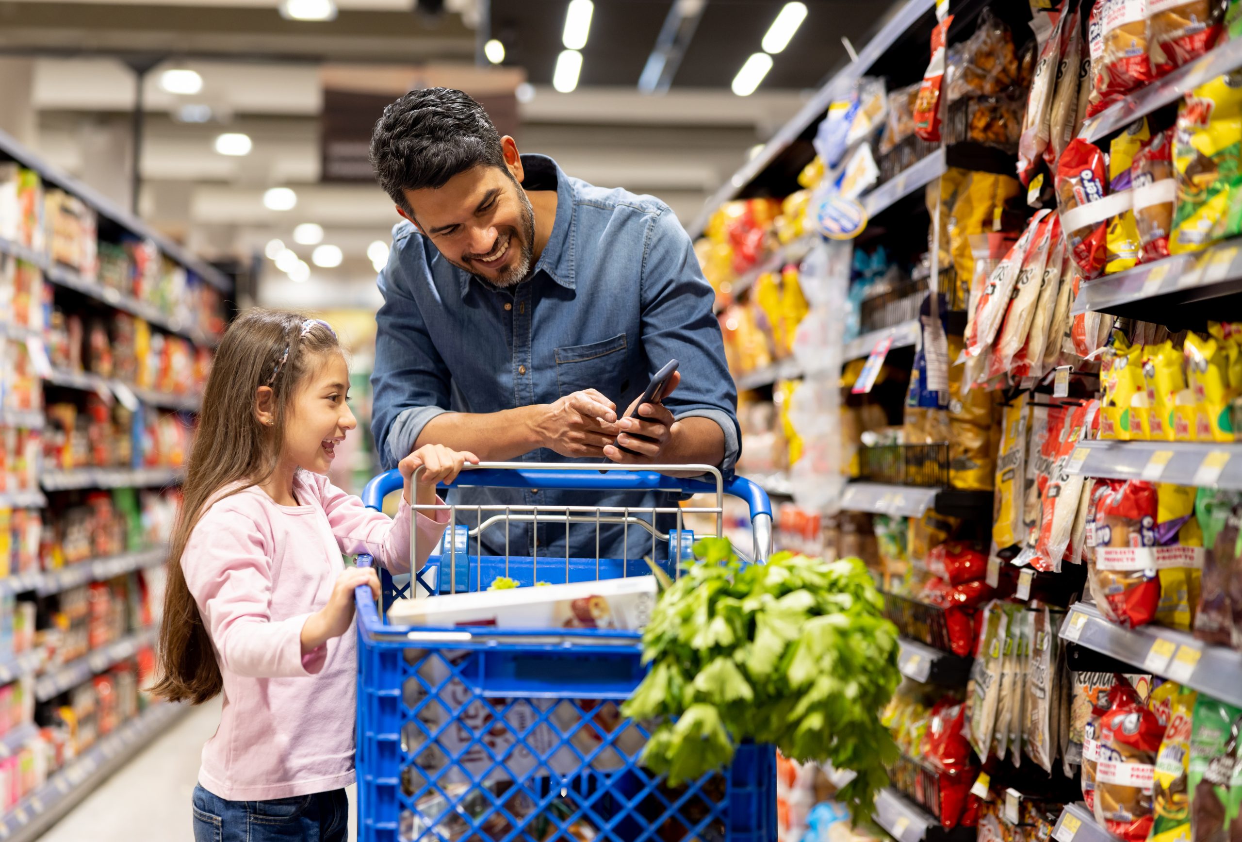 Father and daughter shopping at the supermarket following a list Father and daughter shopping at the supermarket following a list