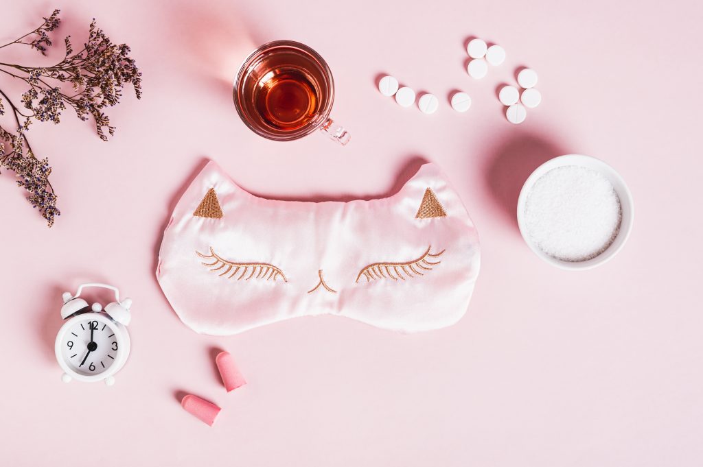 Concept insomnia accessories and sleep medications on pink background top view