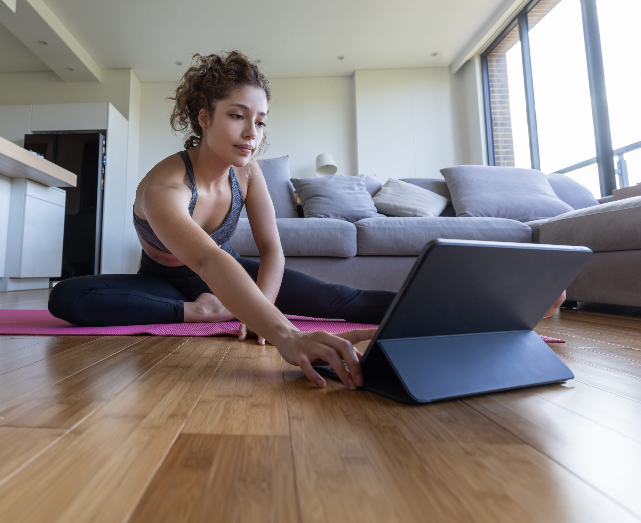 Woman at home following an online fitness class on her tablet